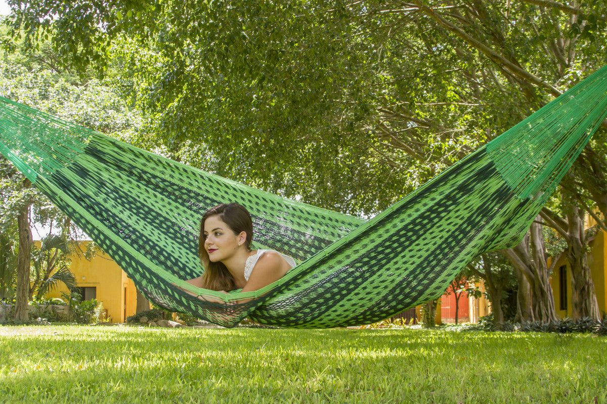 Woman relaxing in a green hammock under a tree