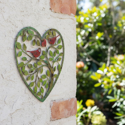 Decorative metal wall art in the shape of a heart with birds and leaves on a white background